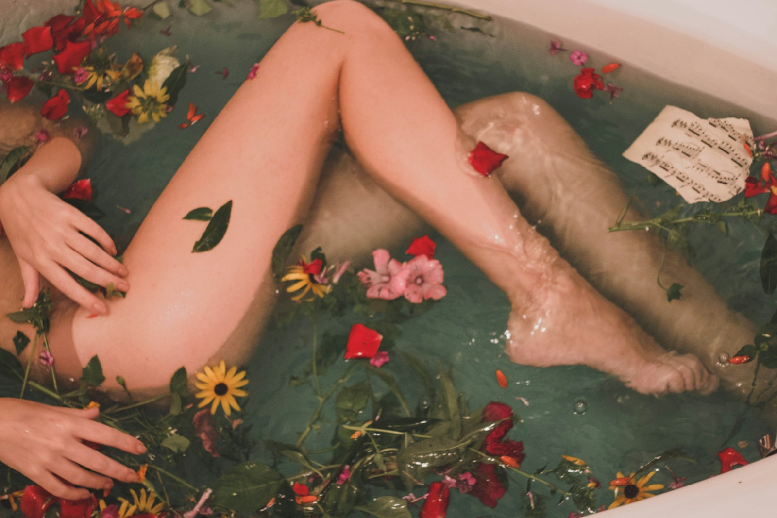 bathtub with water and flowers - yoni massage