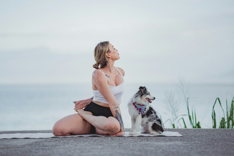 a woman twisting and sitting on a rock with a dog