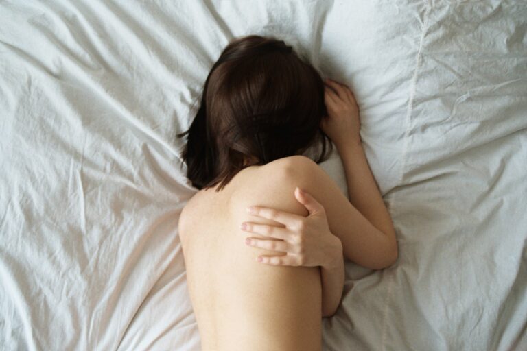 woman hugging herself on bed